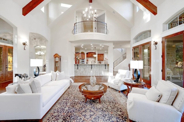 living room with arched walkways, beam ceiling, and an inviting chandelier