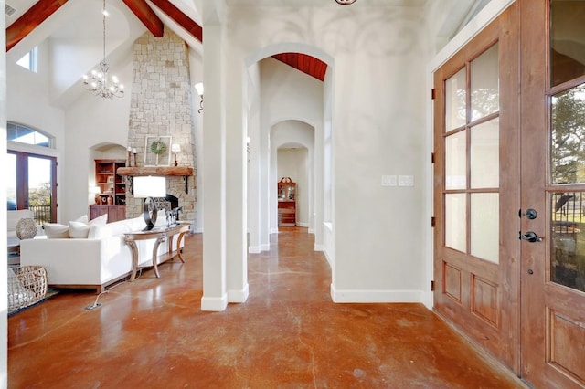 foyer entrance featuring beamed ceiling, french doors, high vaulted ceiling, and concrete floors