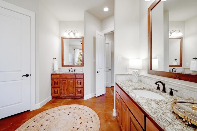 bathroom with a sink, baseboards, two vanities, and finished concrete floors