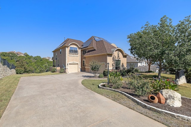 french country home with stucco siding, solar panels, driveway, and fence