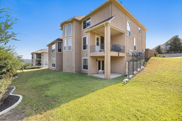 back of property featuring a patio area, stucco siding, a lawn, and a balcony