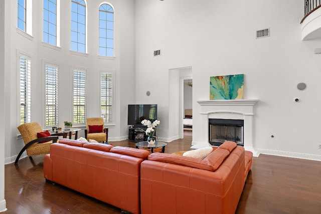 living room with dark wood finished floors, a fireplace with raised hearth, visible vents, and baseboards