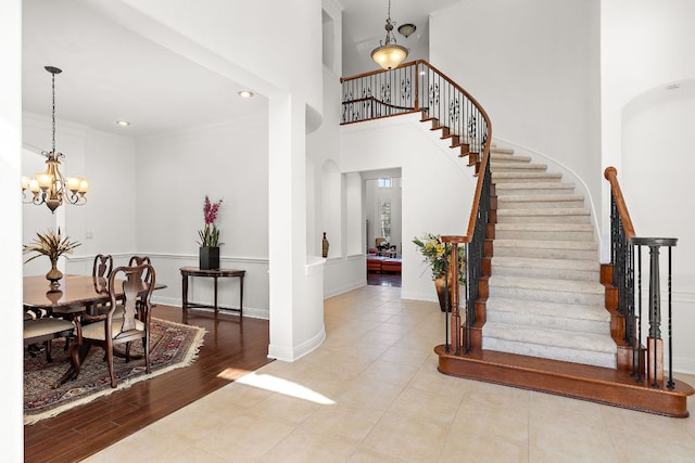 entryway featuring a chandelier, stairway, a high ceiling, wood finished floors, and arched walkways