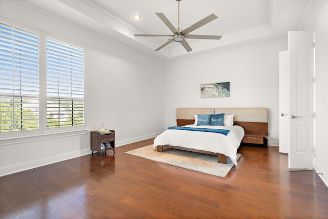 bedroom with a raised ceiling, ornamental molding, wood finished floors, baseboards, and ceiling fan