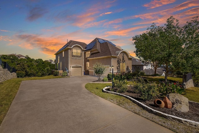 view of front of home featuring stucco siding, a garage, driveway, and fence