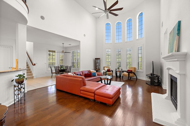 living room with a ceiling fan, hardwood / wood-style flooring, and a fireplace with raised hearth