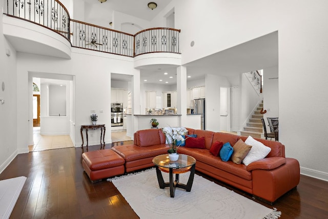 living area featuring baseboards, a high ceiling, stairs, and hardwood / wood-style flooring