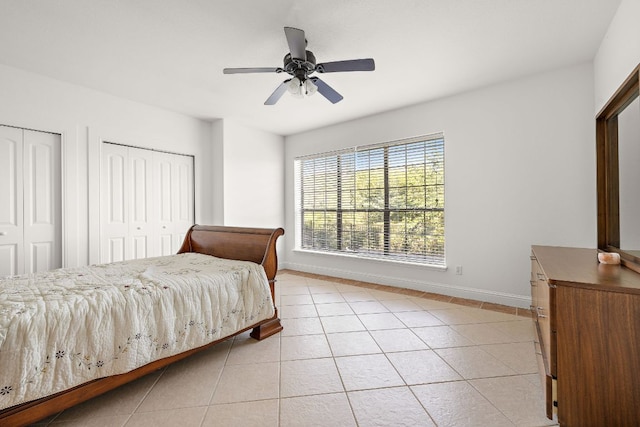 bedroom with ceiling fan, baseboards, two closets, and light tile patterned flooring