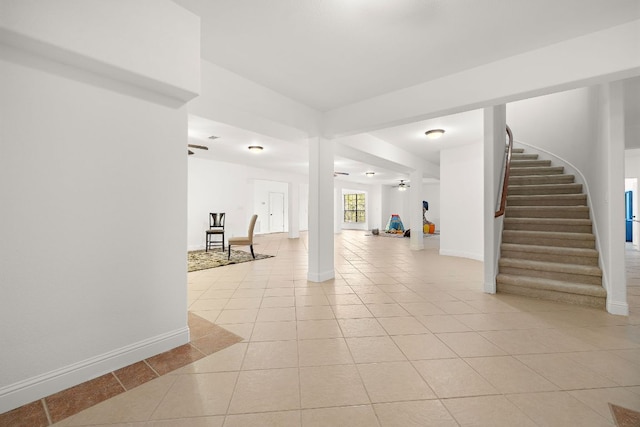 basement featuring stairway, light tile patterned floors, and baseboards