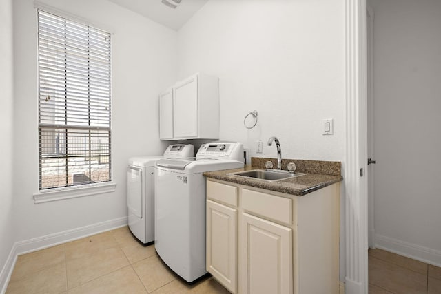 laundry area featuring light tile patterned floors, baseboards, cabinet space, a sink, and washing machine and dryer