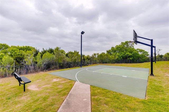 view of basketball court featuring a lawn, community basketball court, and fence