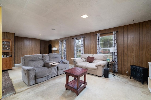 carpeted living area featuring wood walls and a wood stove