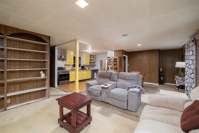 living room featuring built in shelves, visible vents, and wood walls