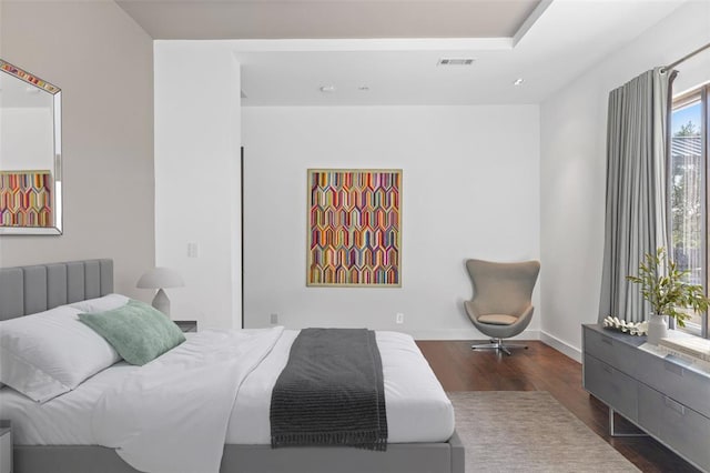 bedroom with visible vents, baseboards, and wood finished floors