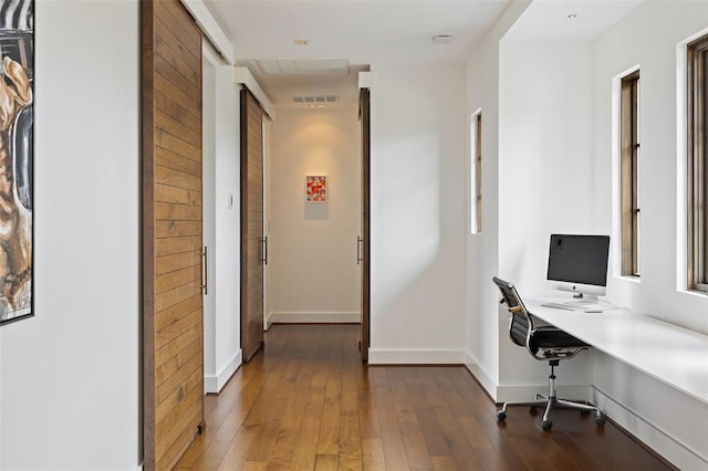 home office featuring visible vents, baseboards, hardwood / wood-style floors, and built in study area