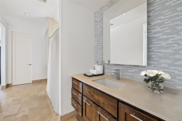 bathroom featuring backsplash, vanity, and baseboards