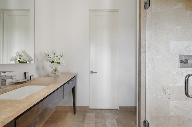 bathroom with a shower stall, vanity, and baseboards