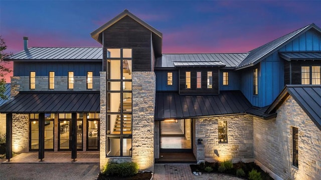 exterior space with a standing seam roof, board and batten siding, stone siding, and metal roof