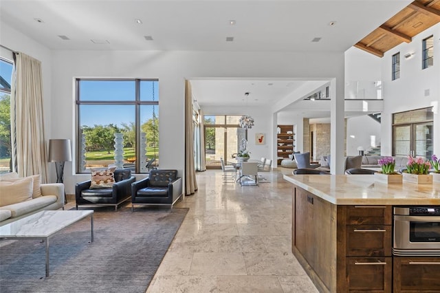 kitchen featuring stainless steel oven, beamed ceiling, open floor plan, and a towering ceiling