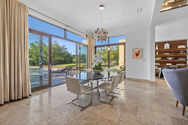 dining room featuring stone tile flooring, a notable chandelier, and baseboards