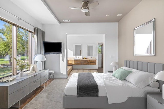 bedroom with visible vents, multiple windows, ensuite bath, and wood finished floors