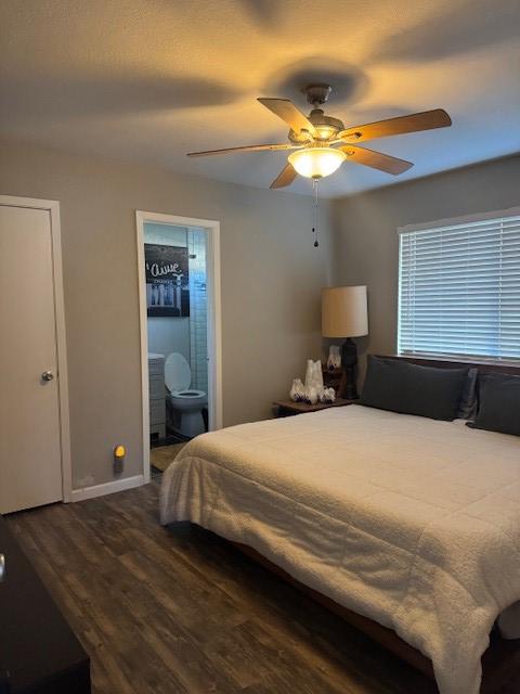 bedroom with a ceiling fan, baseboards, dark wood-type flooring, and ensuite bathroom