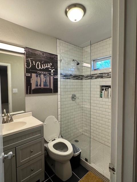 full bathroom with vanity, tile patterned floors, toilet, and a stall shower