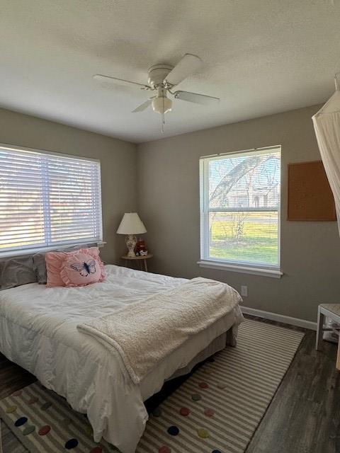 bedroom featuring a ceiling fan, baseboards, and dark wood-style flooring