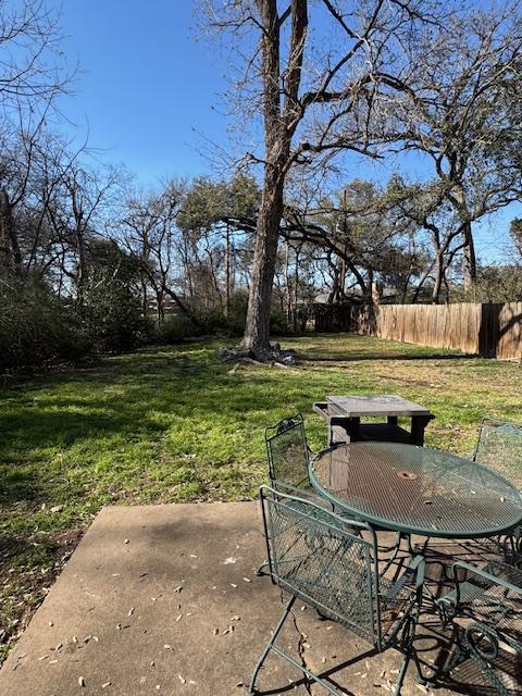 view of yard featuring a patio, outdoor dining space, and fence