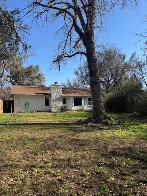 back of property featuring a yard, fence, and a chimney