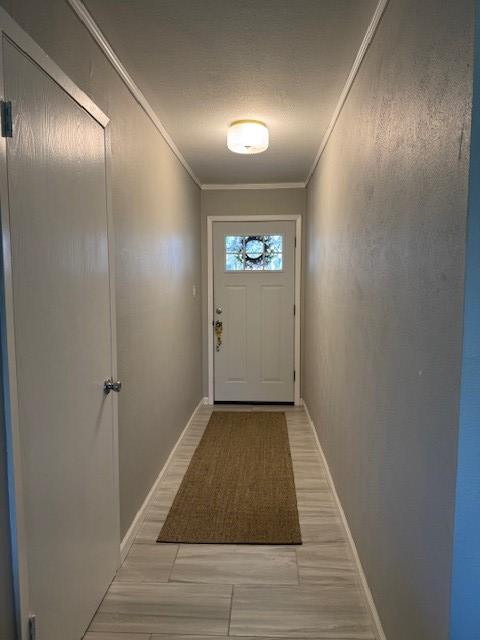 entryway with crown molding, baseboards, and wood tiled floor