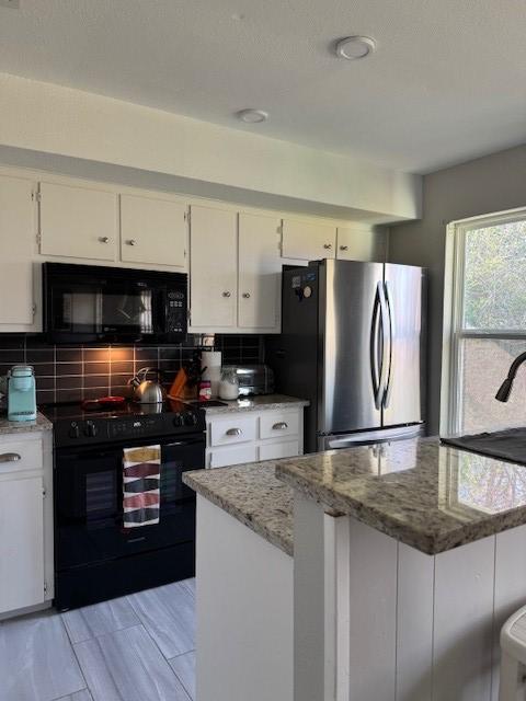 kitchen with light stone counters, tasteful backsplash, black appliances, and white cabinets