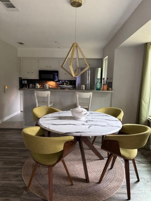 dining space with dark wood finished floors and baseboards
