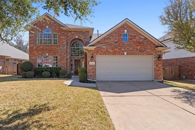 traditional-style house with a front yard, fence, driveway, a garage, and brick siding