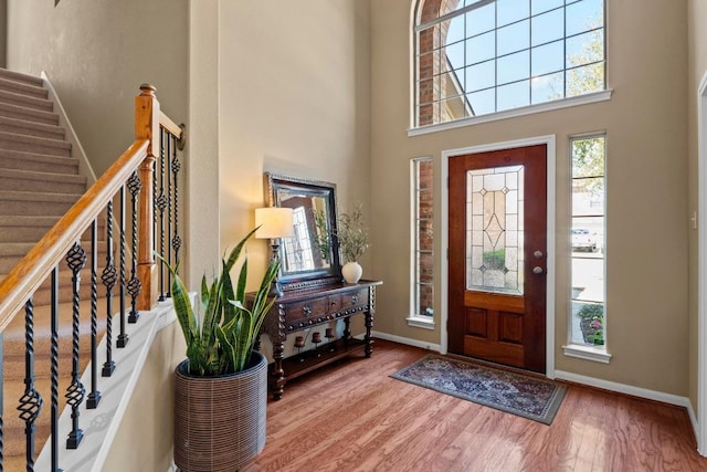 entrance foyer featuring stairs, a high ceiling, baseboards, and wood finished floors