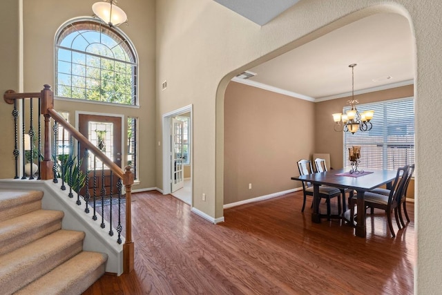 entrance foyer with crown molding, wood finished floors, arched walkways, and baseboards