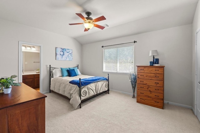 bedroom with baseboards, light carpet, lofted ceiling, and ensuite bath