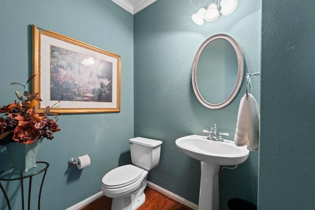 half bathroom with wood finished floors, baseboards, crown molding, toilet, and a textured wall