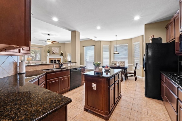 kitchen with a fireplace, ceiling fan, a sink, black appliances, and a center island