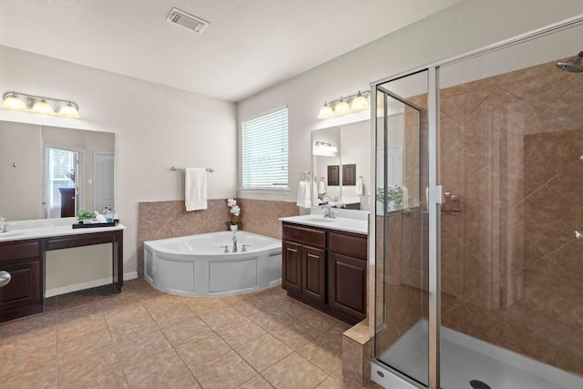 bathroom with visible vents, a garden tub, two vanities, and a shower stall