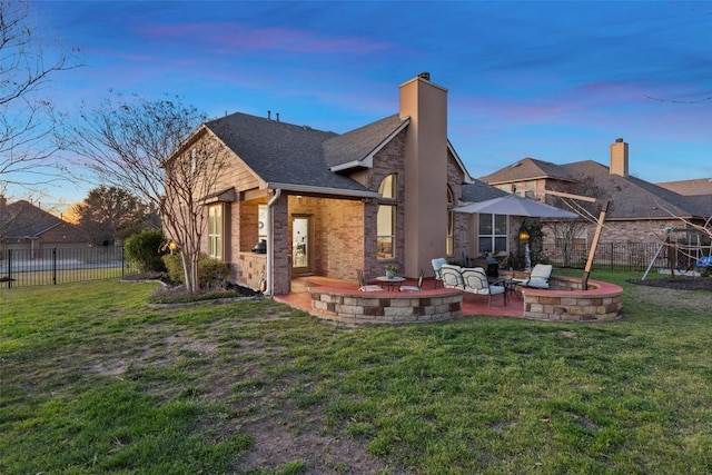 rear view of property with a patio area, a lawn, brick siding, and fence