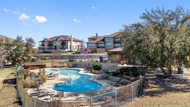 community pool featuring a residential view, a patio, and fence