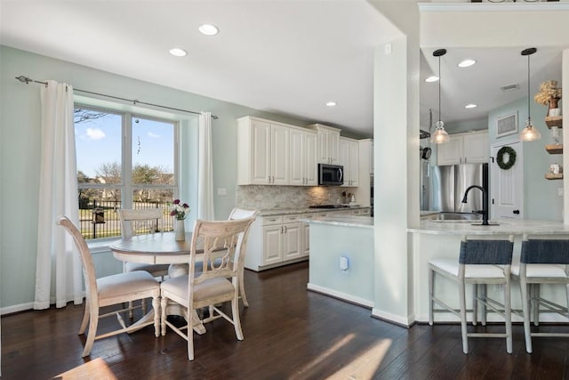 kitchen with dark wood finished floors, white cabinetry, tasteful backsplash, and appliances with stainless steel finishes