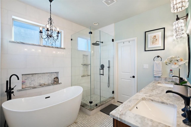 bathroom featuring visible vents, an inviting chandelier, double vanity, a freestanding tub, and a sink