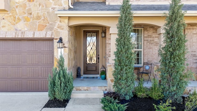 property entrance featuring stone siding, brick siding, a garage, and roof with shingles