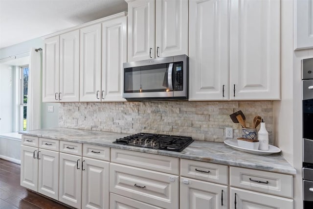 kitchen featuring stainless steel appliances, white cabinets, and decorative backsplash