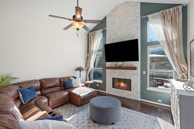 living area featuring wood finished floors, baseboards, high vaulted ceiling, a fireplace, and ceiling fan