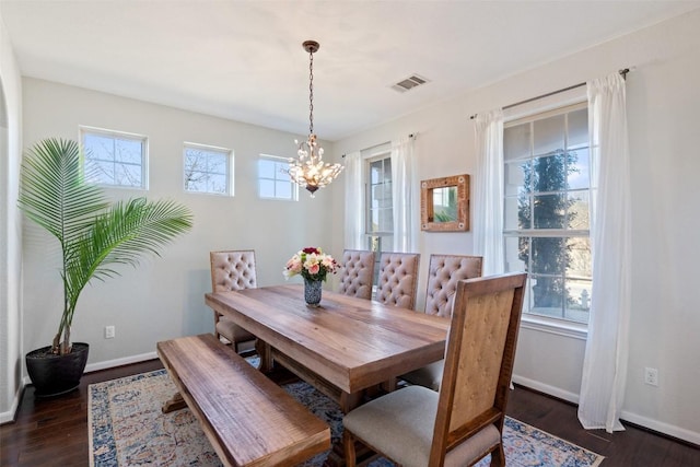 dining area featuring a notable chandelier, visible vents, baseboards, and dark wood-style flooring