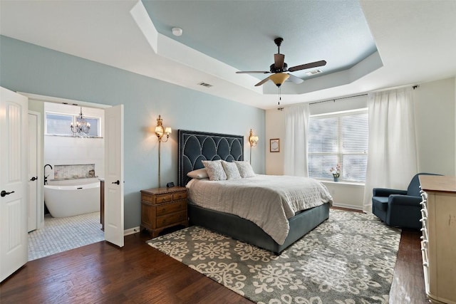 bedroom with visible vents, baseboards, ceiling fan with notable chandelier, wood finished floors, and a raised ceiling