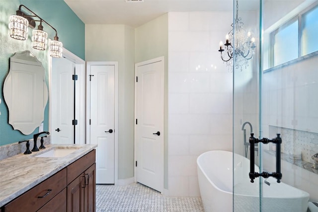 bathroom with tile patterned flooring, vanity, an inviting chandelier, and a freestanding tub